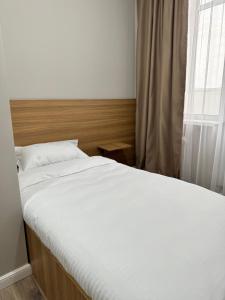 Una cama grande en un dormitorio con ventana. en Uide hotel, en Almaty 6 fotos más