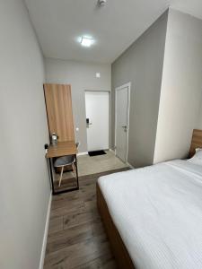 Un dormitorio con una cama y un escritorio con una silla. en Uide hotel, en Almaty