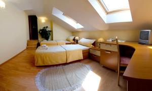 a bedroom with two beds and a desk with a tv at The Rooms by Dalia in Košice