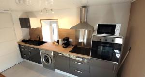 a kitchen with a sink and a microwave and a stove at Gîte Le Bosquet in Mariac