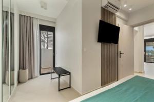 1 dormitorio con TV de pantalla plana y silla en Mella Roa - Ivory, en Nydri