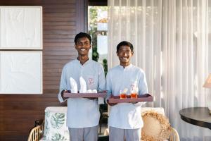 zwei Männer in weißen Uniformen halten ein Tablett mit Essen in der Unterkunft LohonoStays Amani Villa 11B in Coonoor