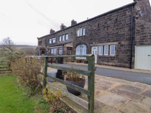 an old brick building with a fence in front of it at Popples Barn in Hebden Bridge
