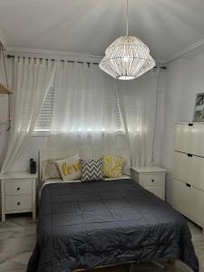a bedroom with a bed with curtains and a chandelier at Acogedor al lado de el mar in Roquetas de Mar