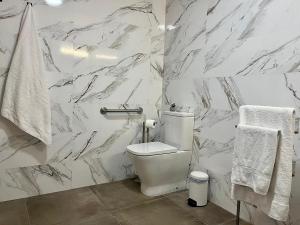 a white bathroom with a toilet and marble walls at New Víctor Villegas Auditorium y FICA AP2 in Murcia