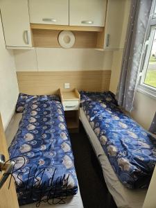 a small room with two beds and a window at Starview 8 berth Caravan in Chapel Saint Leonards +9 photos