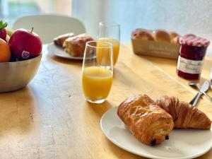 una mesa con un plato de bollería y un vaso de zumo de naranja en " Le nid de Peyramont " Centre ville - Balcon - WiFi, en Muret