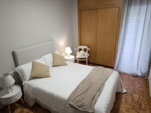 a bedroom with a white bed and a chair at Casa Filo in Redondela