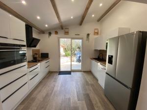 Una cocina con gabinetes blancos y un refrigerador. en Pavillondulantana, en Les Taillades