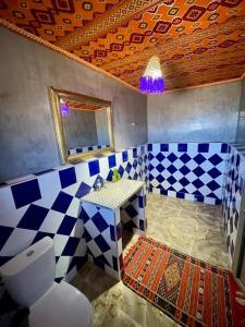 un bagno bianco e blu con servizi igienici e specchio di Chigaga Desert Camp a M'Hamid