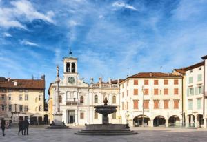 a building with a clock tower and a fountain at Piazza San Giacomo - Elegant Apartment in Udine