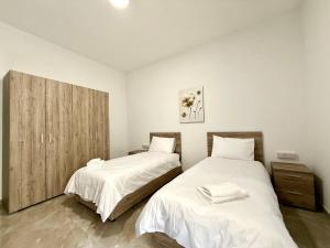 a bedroom with two beds and a wooden cabinet at New Apartment! Walking distance to the three cities by SF Homes in Tal-Borġ