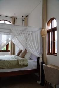 een hemelbed in een kamer met ramen bij The Green Atelier Bali in Jimbaran