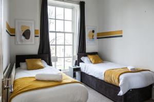 a bedroom with two beds and a window at Contemporary 2-Bedroom Apartment with 4 Beds, Free Parking, Extended Stay Savings in Birkenhead