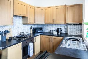 a kitchen with wooden cabinets and black counter tops at Contemporary 2-Bedroom Apartment with 4 Beds, Free Parking, Extended Stay Savings in Birkenhead +29 photos