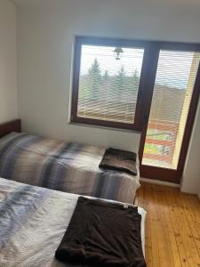 een slaapkamer met twee bedden en een groot raam bij Resort Stari Bagrem Tvrdimici in Tvrdimići