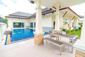 a patio with a table and a swimming pool at Royal Elephant Pool Villa in Na Jomtien