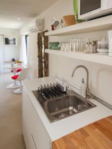 a kitchen with a sink in a white kitchen at charming studio in the house of Envi's house in Sant Josep