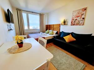 ein Wohnzimmer mit einer schwarzen Couch und einem Tisch in der Unterkunft LIVE-INN PRAGUE DELUXE SUITE FOR 1-4 GUESTS, 20 Mins to center, Lift, Gym, Reception, Parking, Roof Terrace, Game & Party in Prag