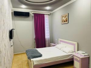 a bedroom with a bed and a purple curtain at Aero Hotel Tour Armenia in Pʼarakʼar
