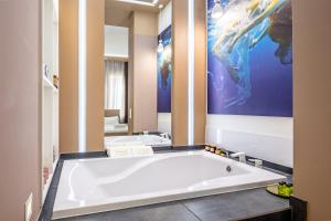 リヴィウにあるAvangard Horodotska 31 Apartのバスルーム(大型バスタブ、絵画付)