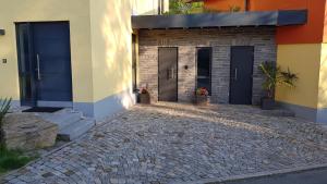 a building with three doors and a brick driveway at Moderne, Niveauvoll Eingerichtete Ferienwohnung in Eibenstock