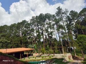 a resort with a pool and a building and trees at Chácara Morada do Sol Ibiúna in Ibiúna