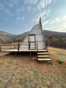 a small house with a porch and stairs in a field at The Tribe, Panchgani Mahableshwar in Wai