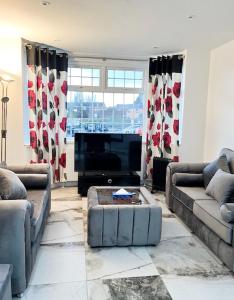 a living room with couches and a flat screen tv at Luxury and spacious 3 bedroom home in Southampton in Southampton