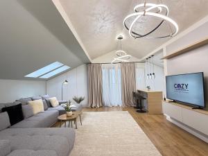 ein Wohnzimmer mit grauem Sofa und einem Fernseher in der Unterkunft COZY Luxury Collection - PREMIUM APARTHOTEL in Braşov