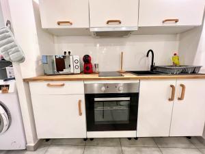 a small kitchen with white cabinets and a stove at O Nid'Istres - Centre Historique, Spacieux Studio Duplex, Wifi, 4 personnes in Istres