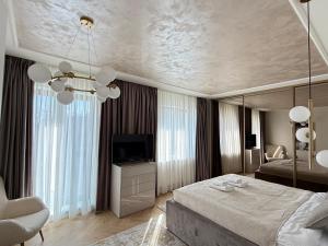 ein Schlafzimmer mit einem großen Bett und einem Fernseher in der Unterkunft COZY Luxury Collection - PREMIUM APARTHOTEL in Braşov