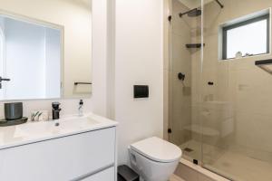 a white bathroom with a toilet and a shower at Diamond Views - Luxury Sea Point Apt with views in Cape Town +13 photos