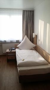 Bett in einem Zimmer mit einem großen Fenster in der Unterkunft Hotel Rheinkrone in Koblenz