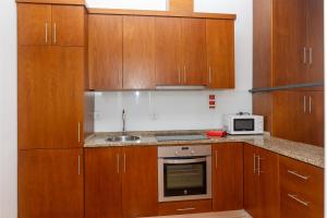 Una cocina con armarios de madera, fregadero y microondas. en Moniz Terrace, en Guimarães 9 fotos más