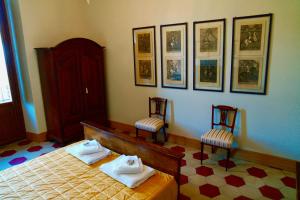 a bedroom with two chairs and a bed and pictures on the wall at The Poets' Retreat in Sulmona