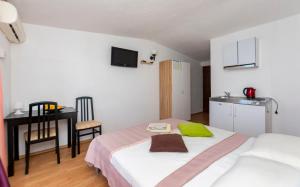a bedroom with a bed and a table and a kitchen at Apartments Luka in Krilo