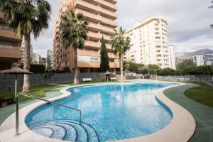 a large swimming pool with palm trees and buildings at Apartamento Benimar III in Cala de Finestrat
