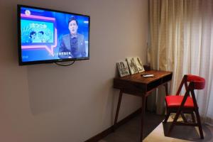 Mowin Boutique Hotel & Residence في بنوم بنه: تلفزيون على جدار مع طاولة وكرسي