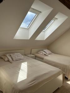 a attic bedroom with two beds and two windows at Apartment Belaj in Celje