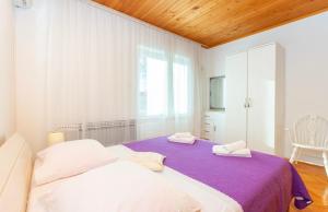 a white bedroom with a purple bed and a window at Apartment LEMONA in Makarska