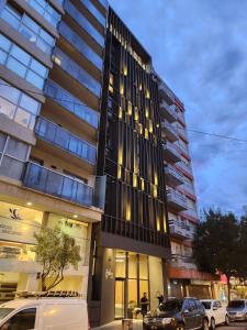 a tall building with cars parked in front of it at Hotel Estilo MB - Mar del Plata in Mar del Plata