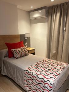 a bedroom with a large bed with a red pillow at Hotel Estilo MB - Mar del Plata in Mar del Plata