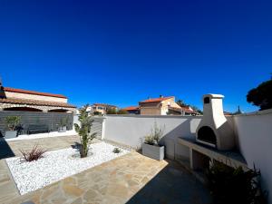 a patio with a pizza oven on a white wall at Maison tout confort au calme idéal famille 4ESTGNT7 in Le Barcarès