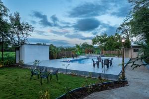 a pool with tables and chairs in a yard at CosmicStays Casa Ivory Private Pool Villa near Mulshi in Mulshi