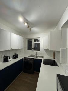 a kitchen with white cabinets and a sink and a dishwasher at The Snug Nest - Modern 2 Bedroom Apartment in Belvedere