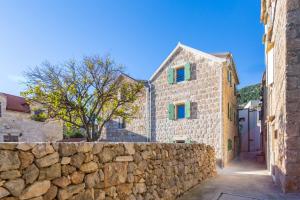 a stone building with green windows and a stone wall at Studio Suites Mila in Komiža +4 photos