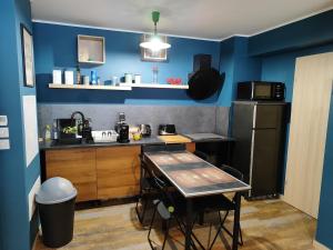 a blue kitchen with a table and a refrigerator at Jolie appartement avec piscine et parking privé Menton in Gorbio