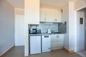 a kitchen with white cabinets and a white refrigerator at Les Marinas front of the beach in Courseulles-sur-Mer