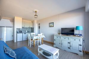 a living room with a blue couch and a kitchen at Les Marinas front of the beach in Courseulles-sur-Mer +18 photos